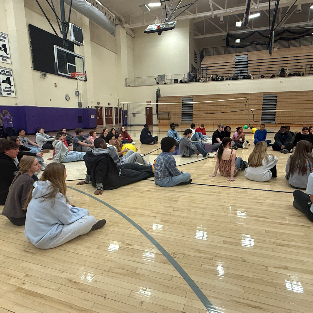 students sitting on gym floor