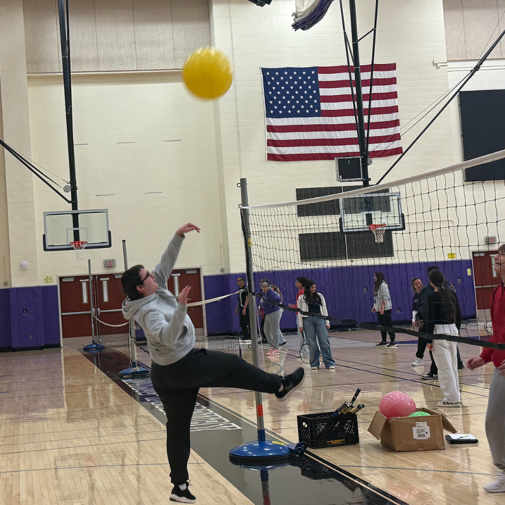 student hitting a ball with american flag in the background