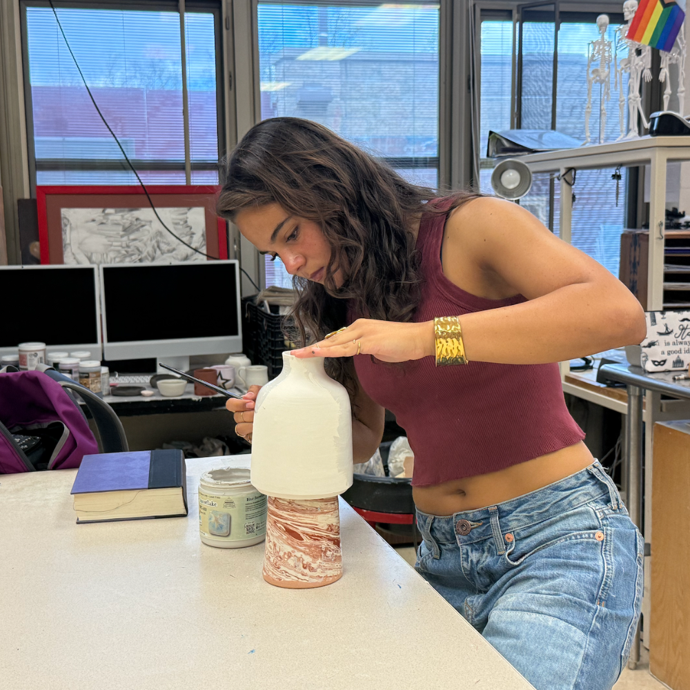 student painting a jug on an art table 