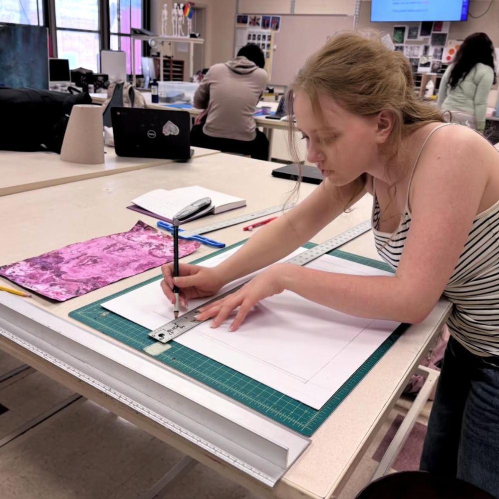 student cutting paper with a ruler on an art table 