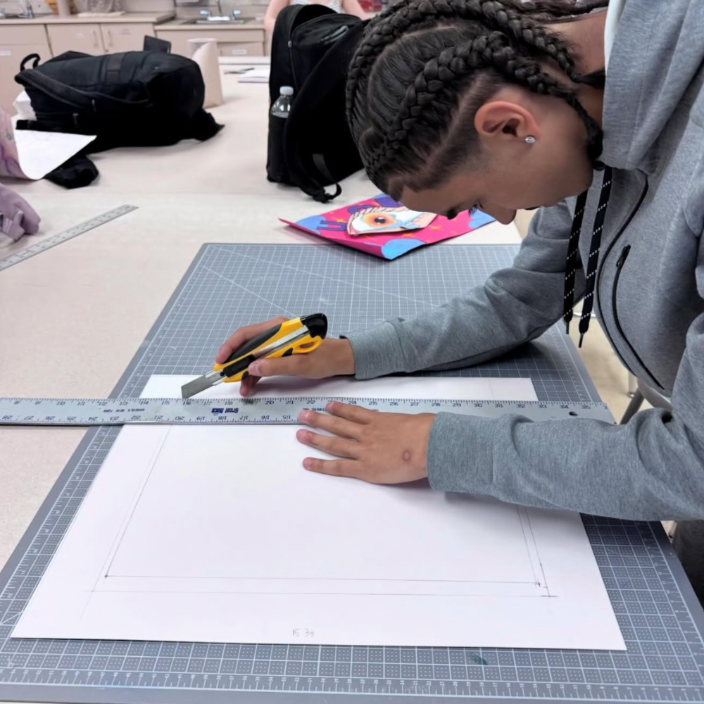 student holding a ruler and a cutting knife