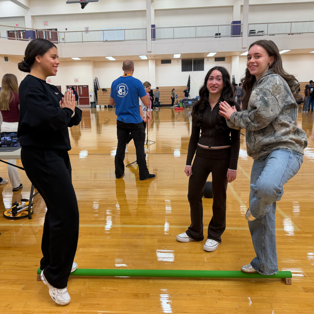 two students standing on long floor pole 