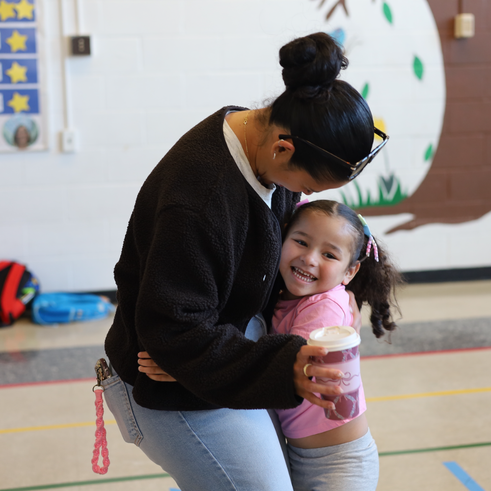 child hugging woman holding cup