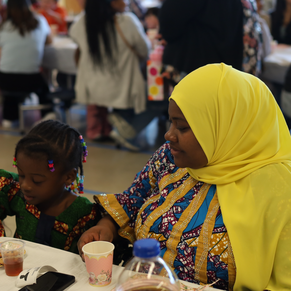 woman with a hijab sitting at a table with a student 
