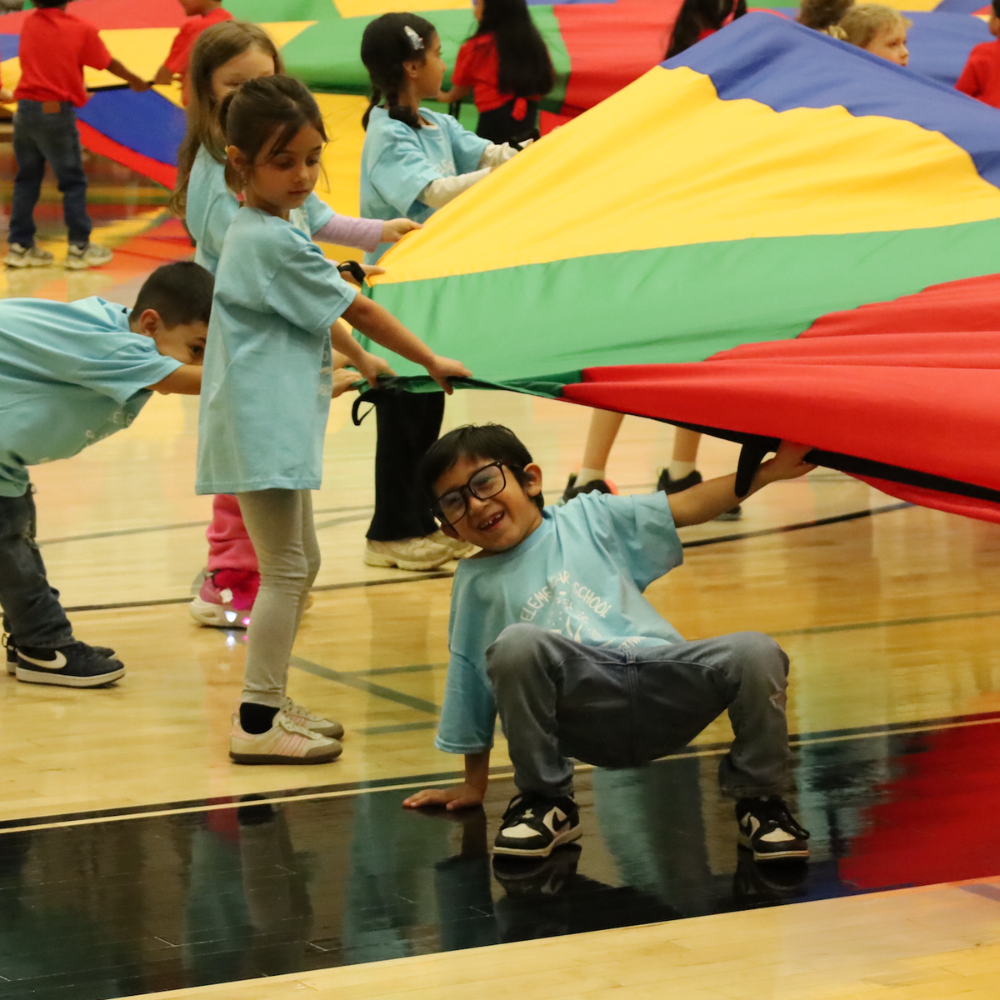 student smiling holding colorful parachute