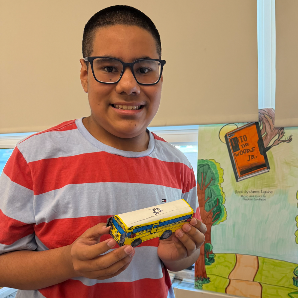 Student with a striped shirt holding a mini school bus