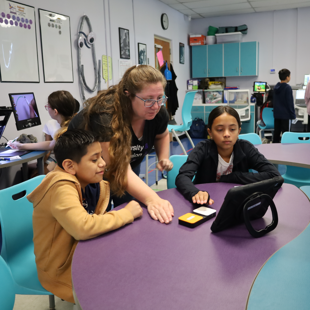 three people leaning over tablet 