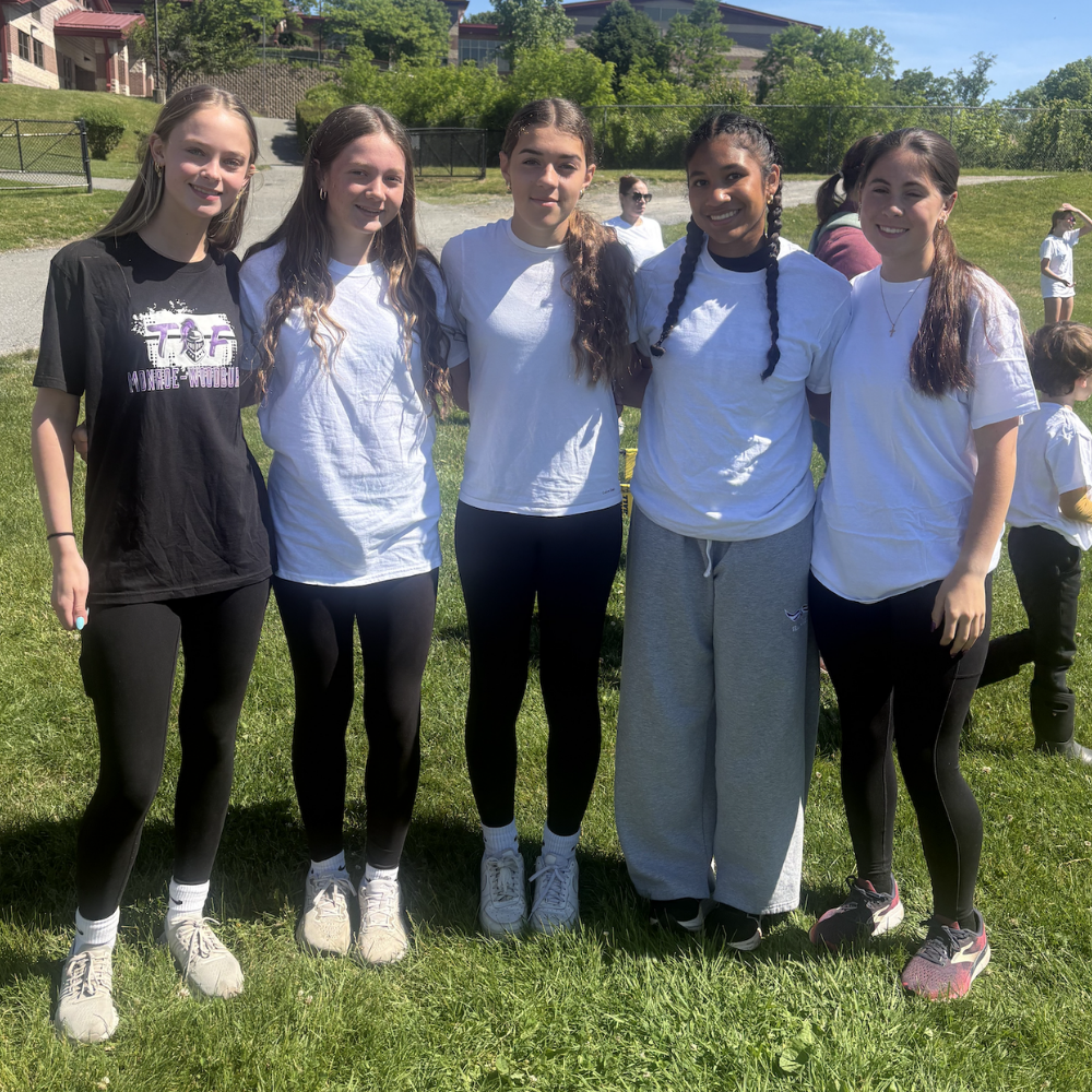 five students standing in grass