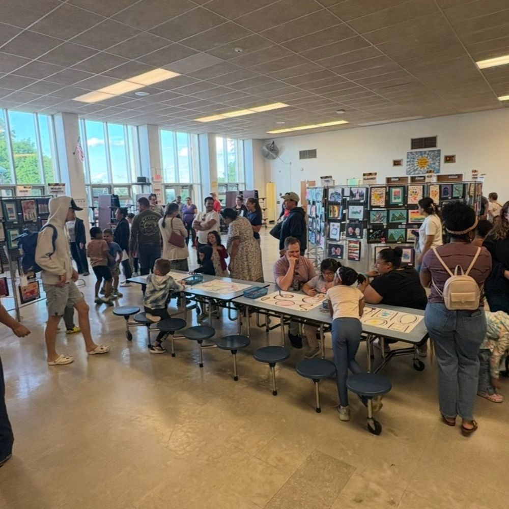 families standing and sitting around blue chairs in cafeteria