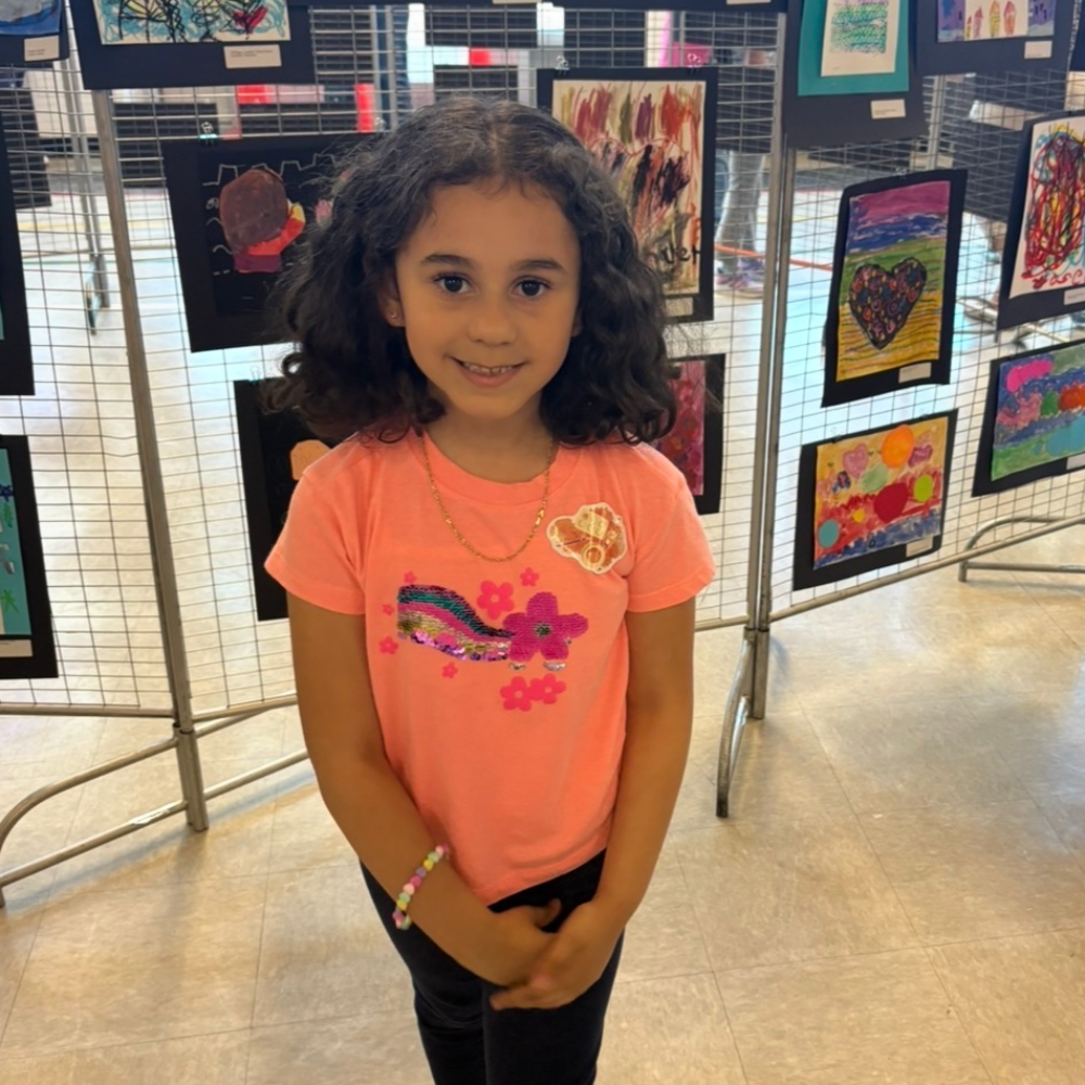 student standing smiling in front of art work 