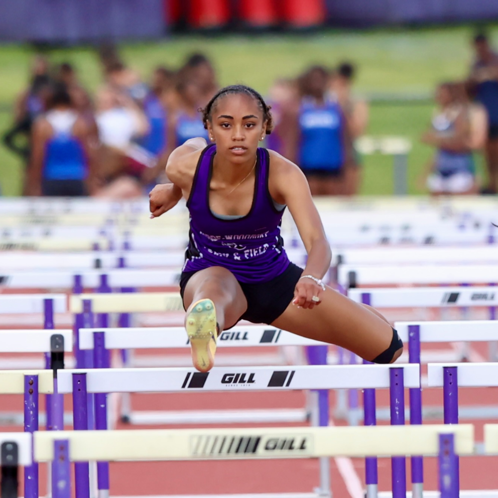 student jumping over hurdle