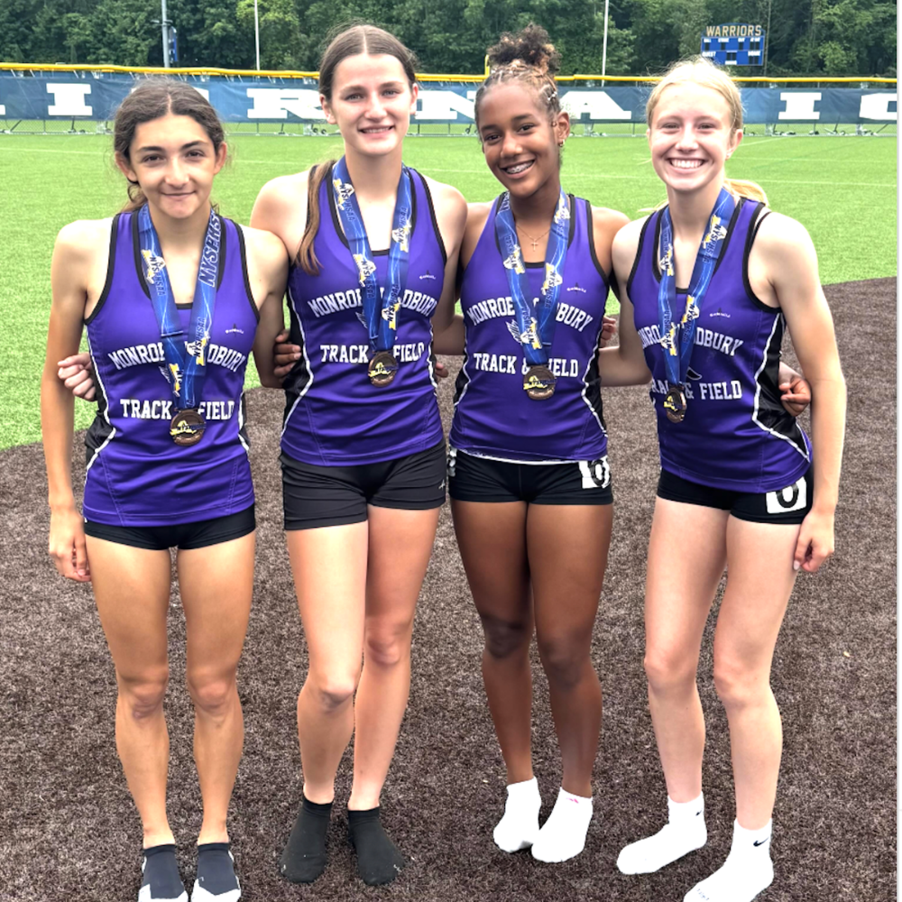 four students standing with medals with shirts that say track and field