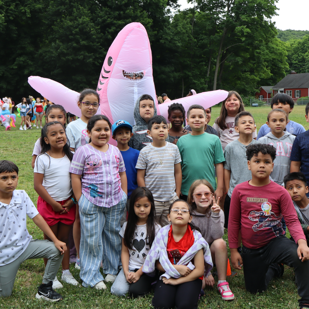 person in pink shark costume posing with kids