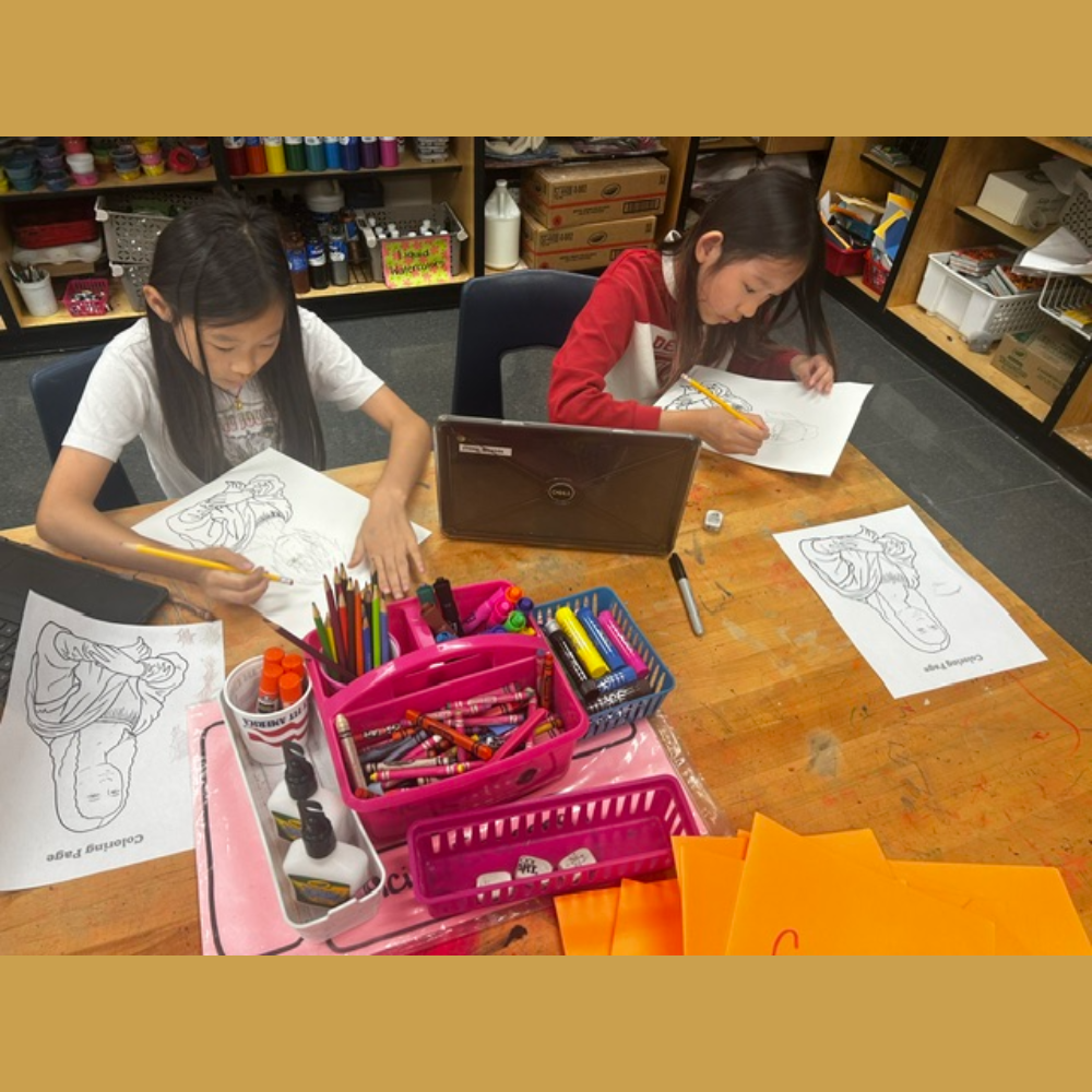 Students sitting an art table drawing and tracing