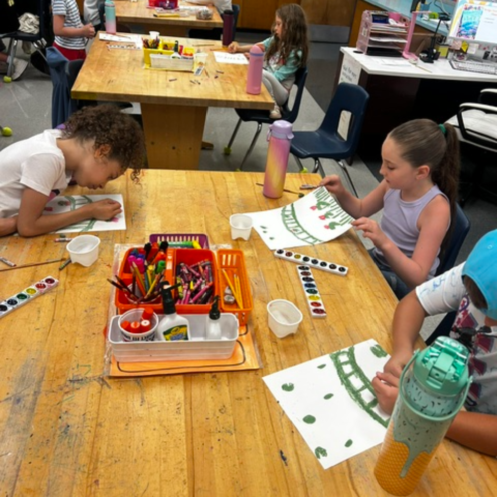 students sitting at a table with paints and water colors