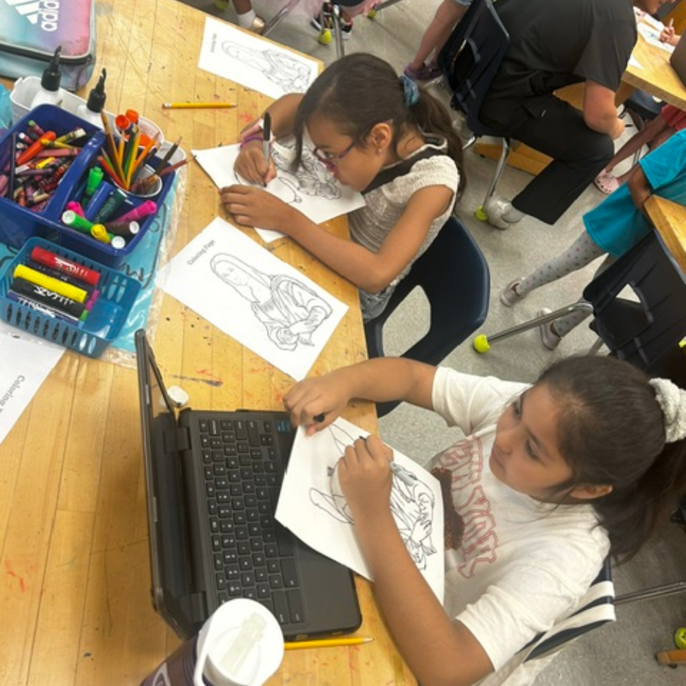 students sitting at a table with a laptop