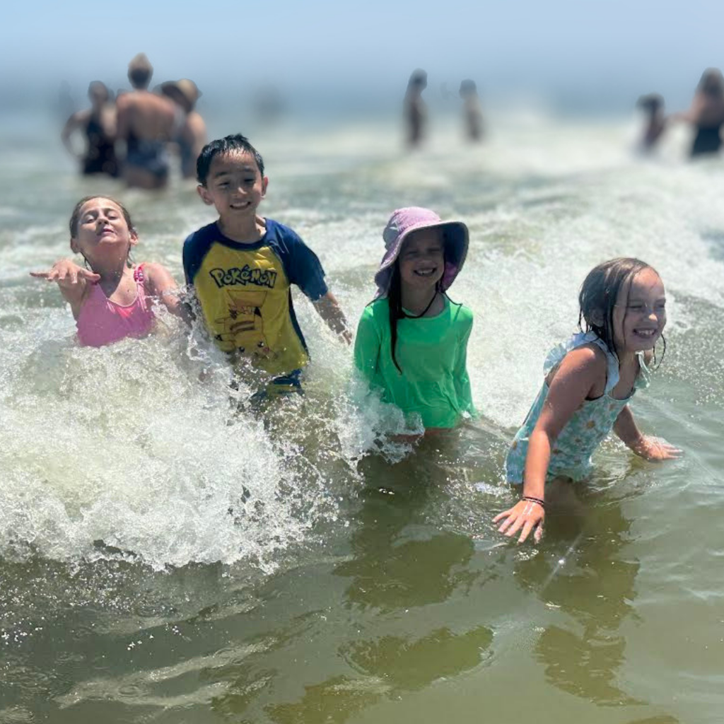 four students enjoying time in the ocean