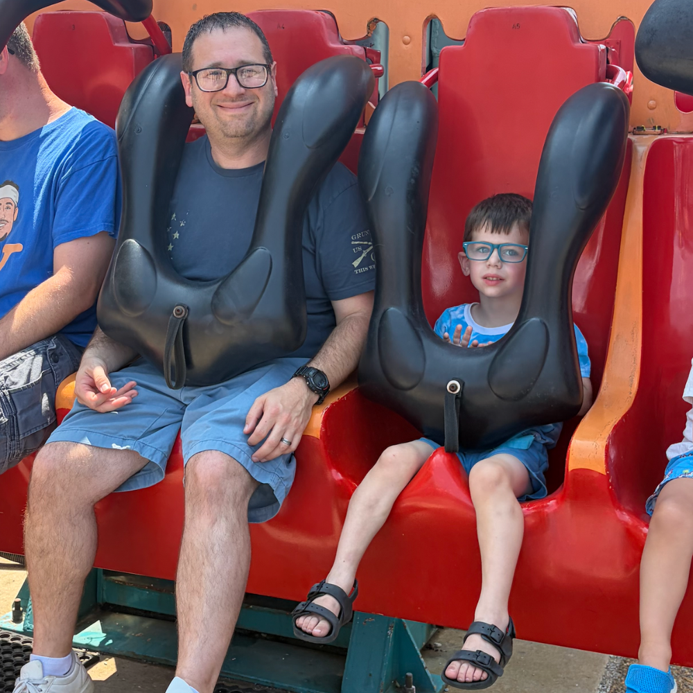 man and boy sitting on  a red ride 