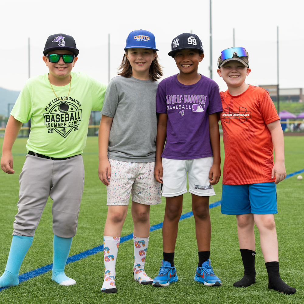 four students standing on a baseball field 