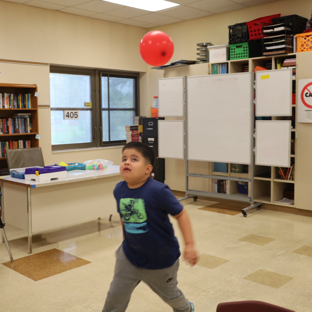 student playing with a red balloon