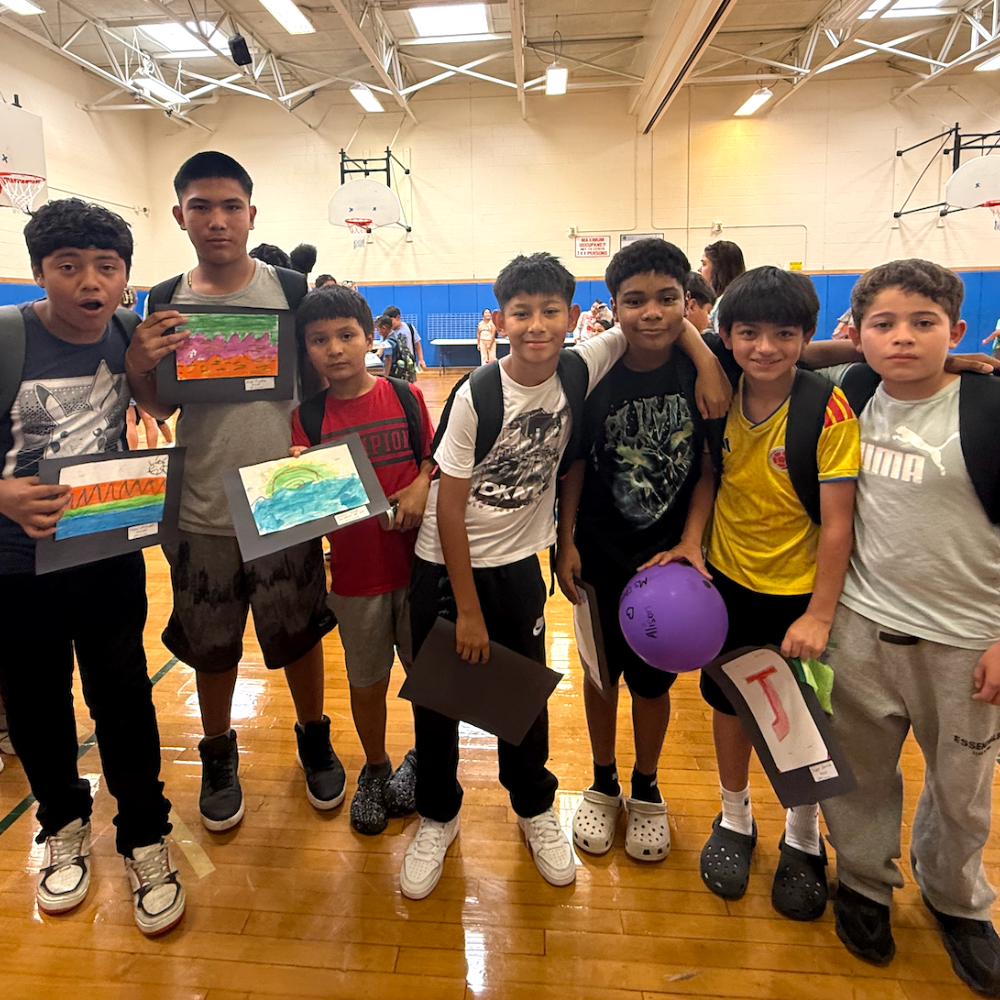 seven students holding artwork and a purple balloon 