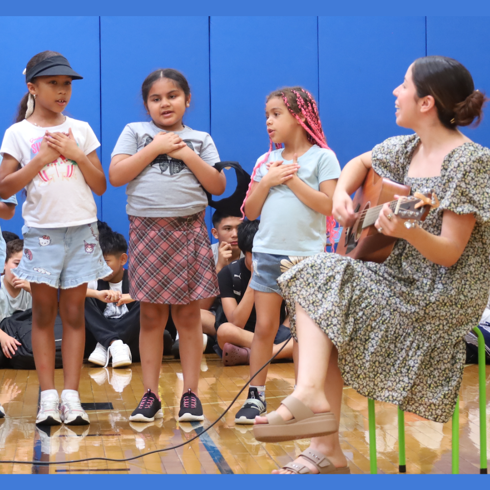 teacher with a guitar singing with three students