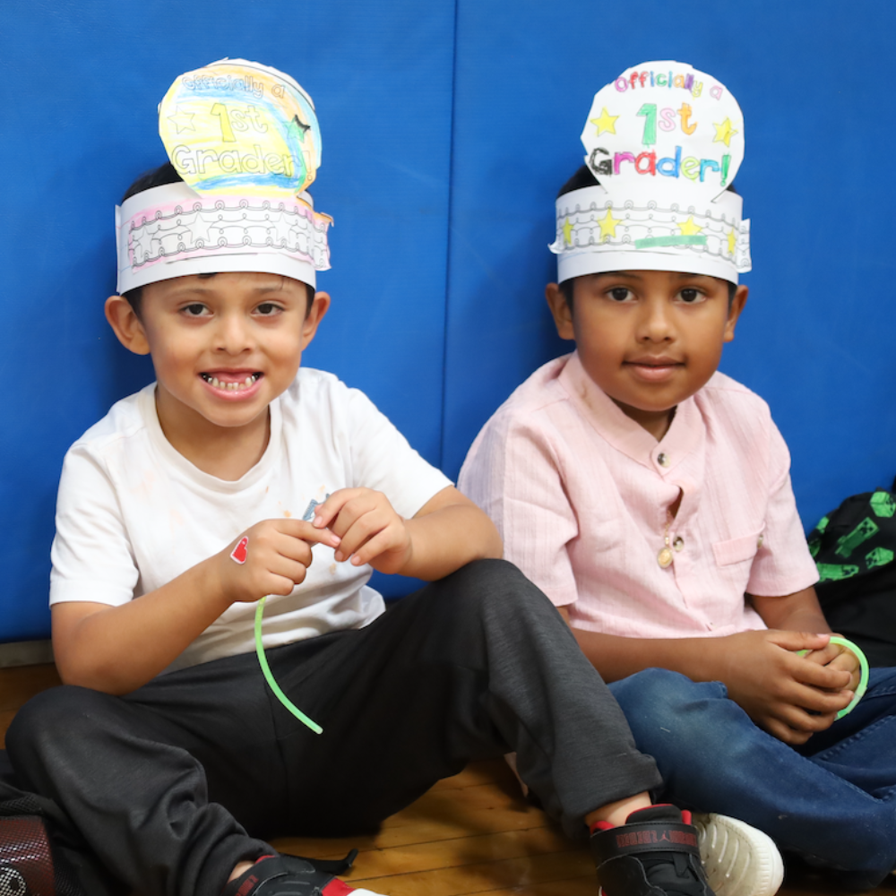 photo of two students with paper hats, officially a 1st grader 