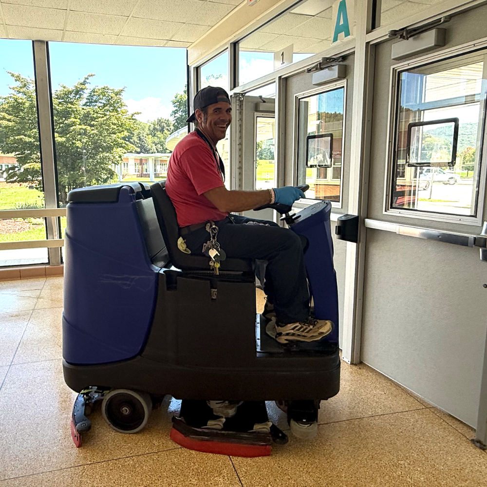 man in a red shirt sitting on a blue cleaning machine