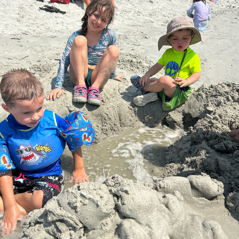 three children sitting in the sand 