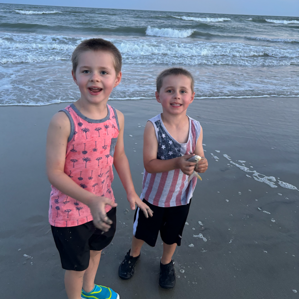 two children standing on the beach with colorful shirts