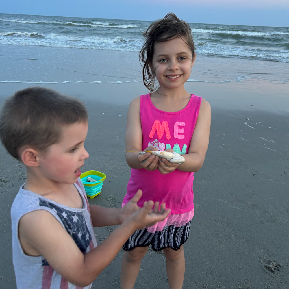 child with a pink shirt that says ME and boy in a tank top on the beach