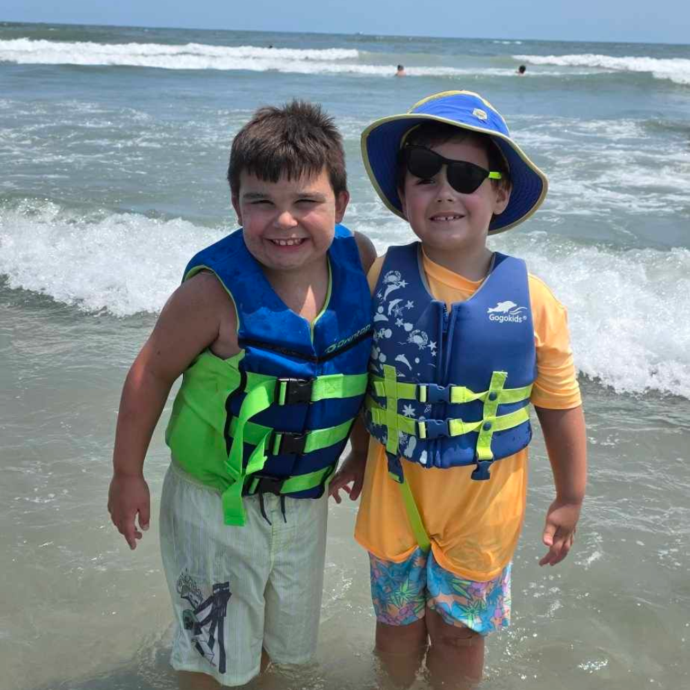 two students at the beach wearing blue water vest 