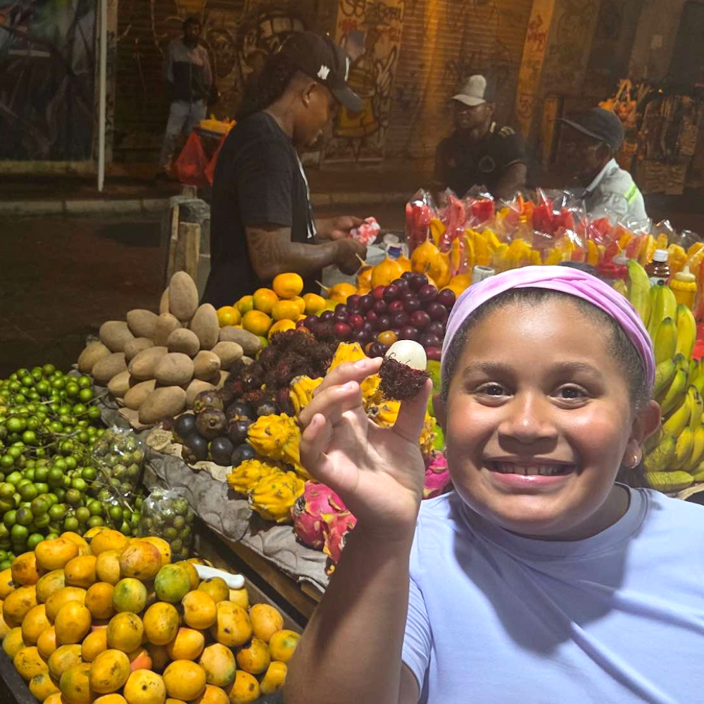 girl standing in front of a fruit stand