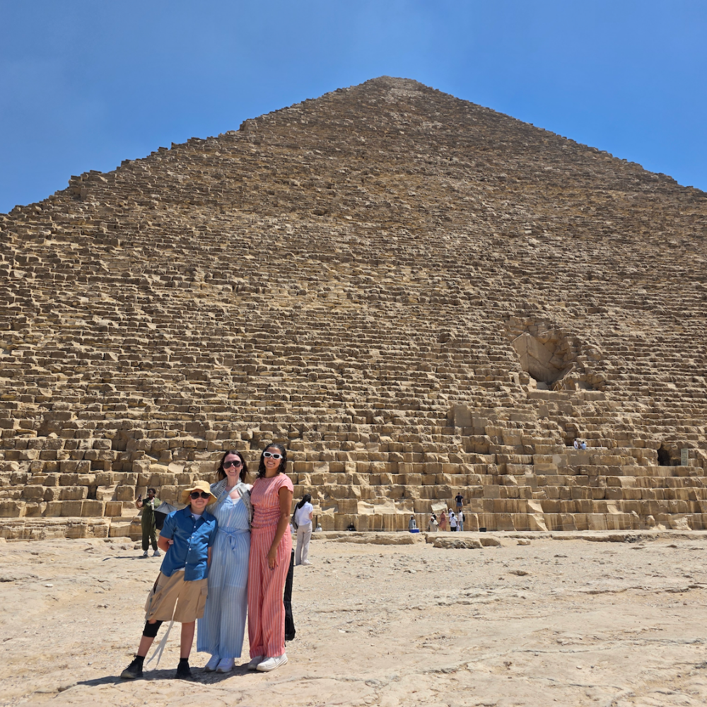 three people standing in front of a pyramid