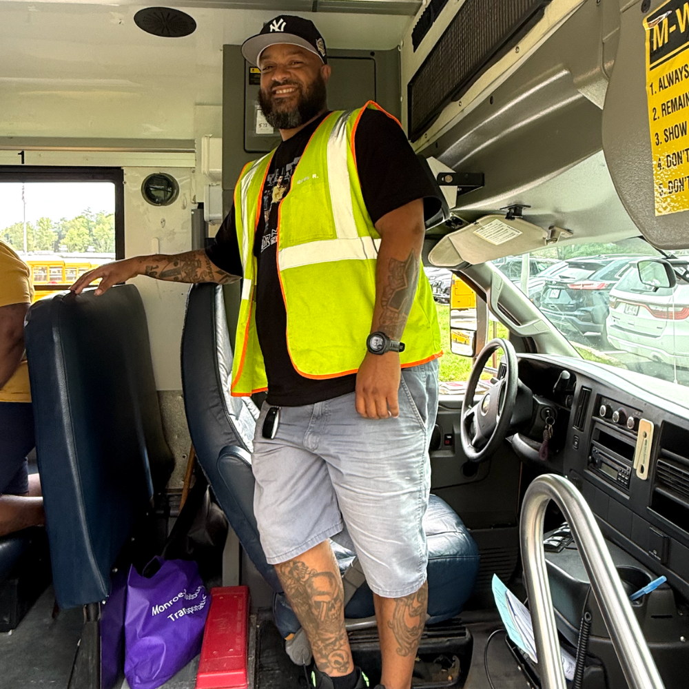 driver with a yellow vest standing on a bus