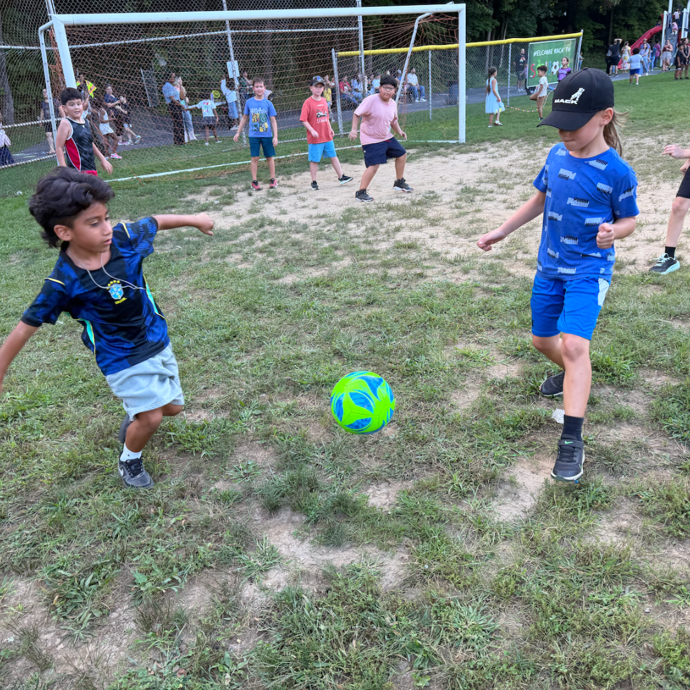 two students wearing blue with a green soccer ball