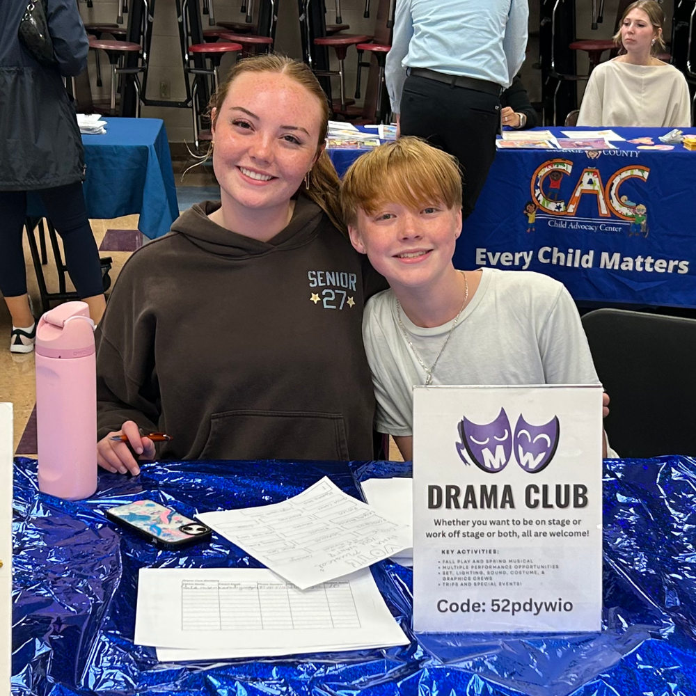 two students sitting at a blue table 