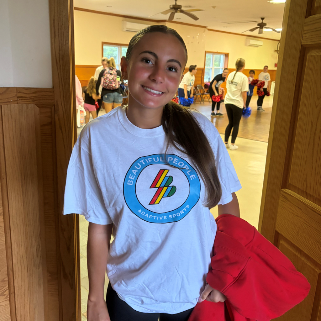 student wearing a white shirt holding a red sweatshirt at a door 