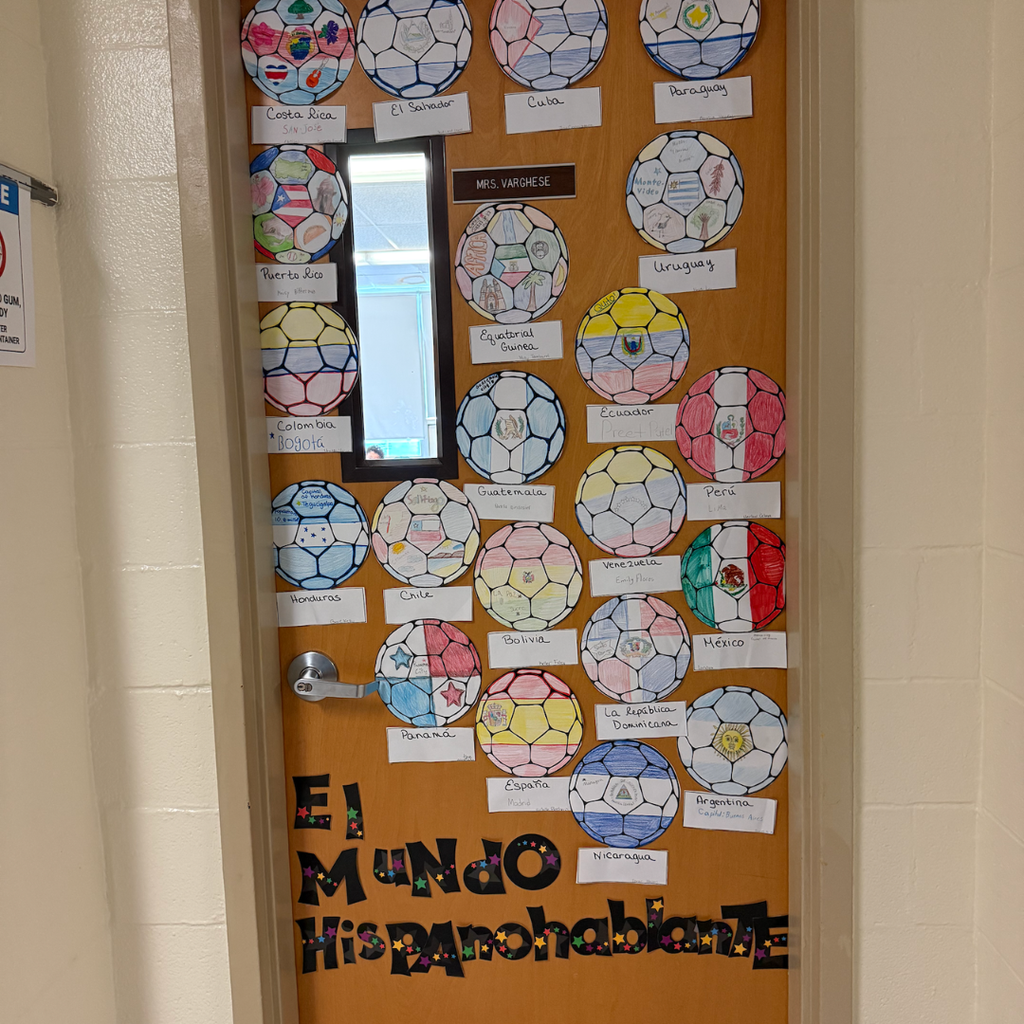 A decorated door with soccer balls, names, and colorful patterns. Words "El Mundo Hispanohablante" are at the bottom.