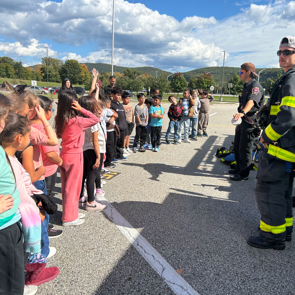 students lined up outside next to fire fighters