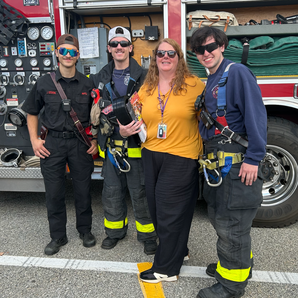 three fire fighters stand with teacher 