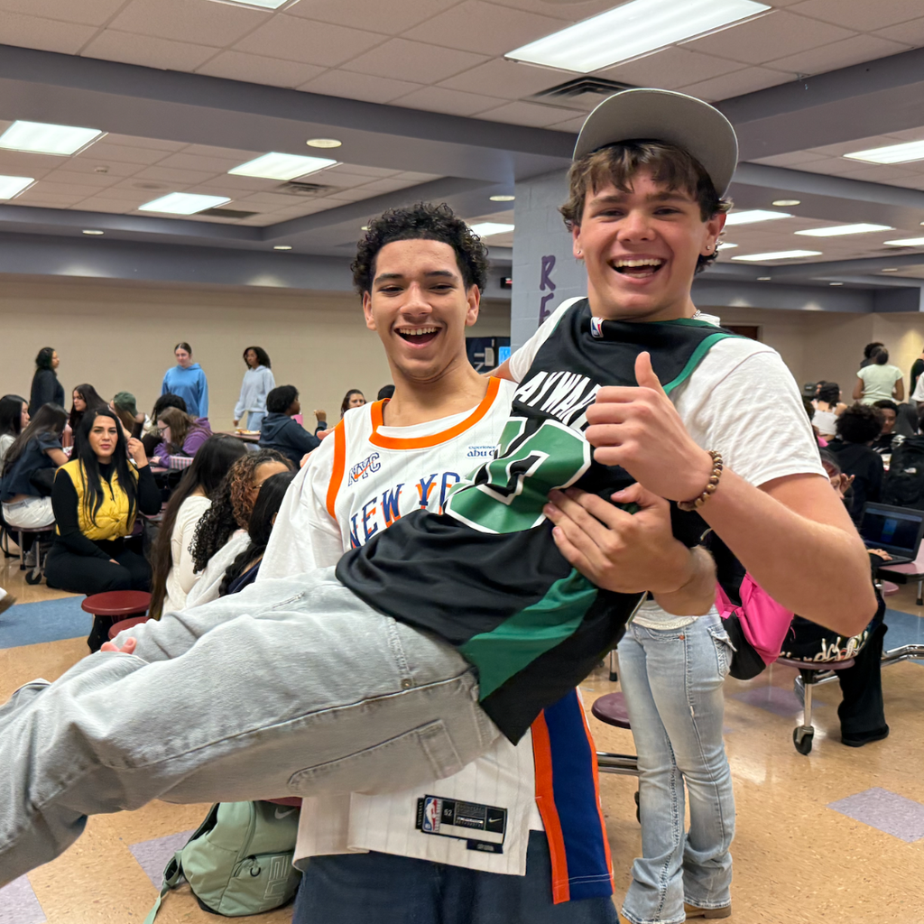 Two boys in school uniforms, one in a black and green jersey