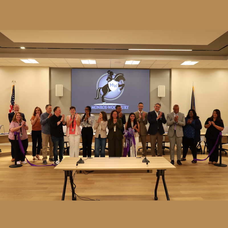 men and women standing in a board room clapping