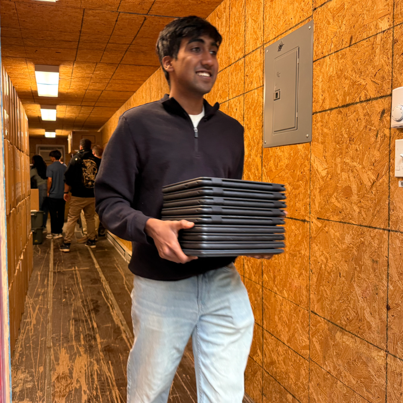 student holding laptops walking down the hall