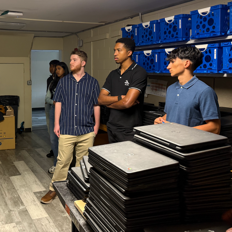 five students standing next to blue boxes with computers