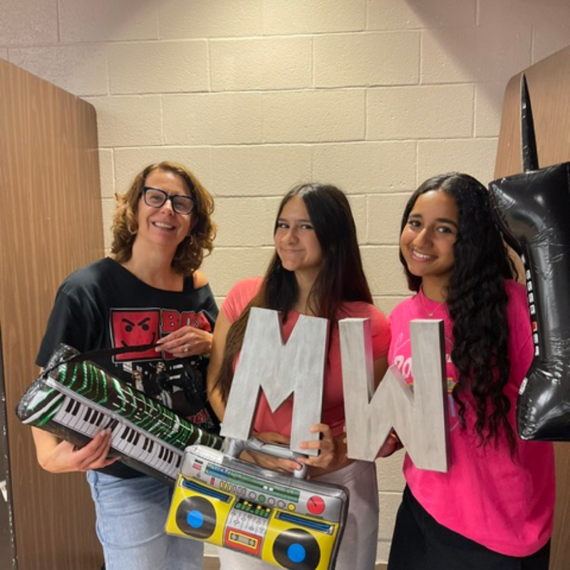 three people standing with MW letters