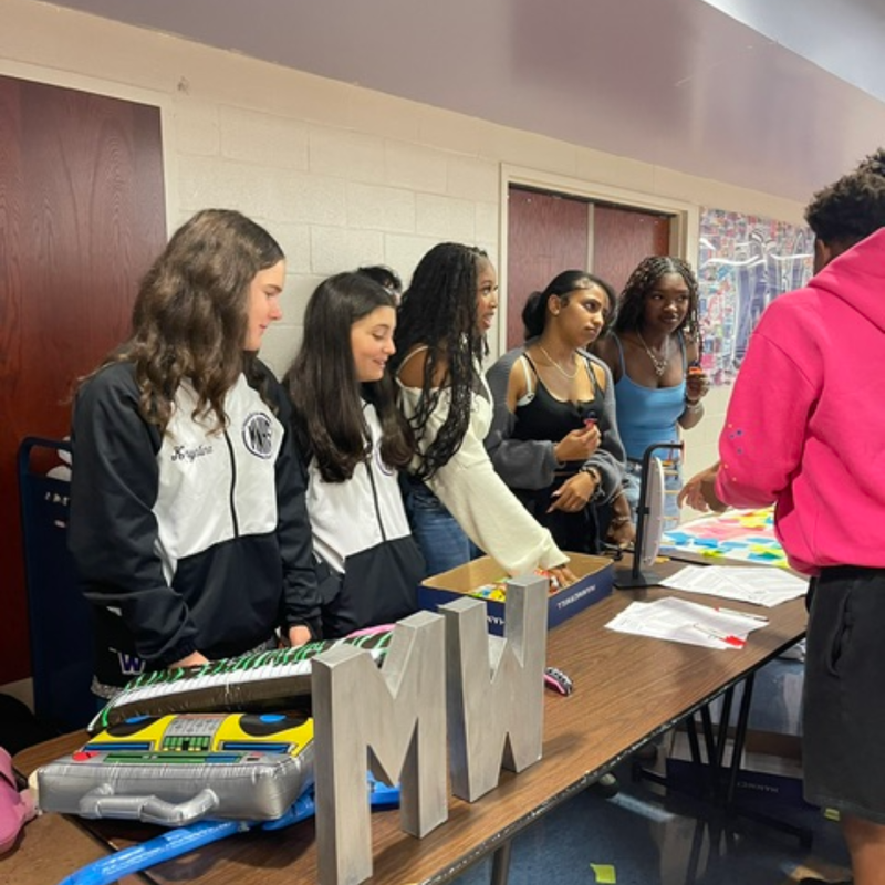 students standing at a brown table with MW