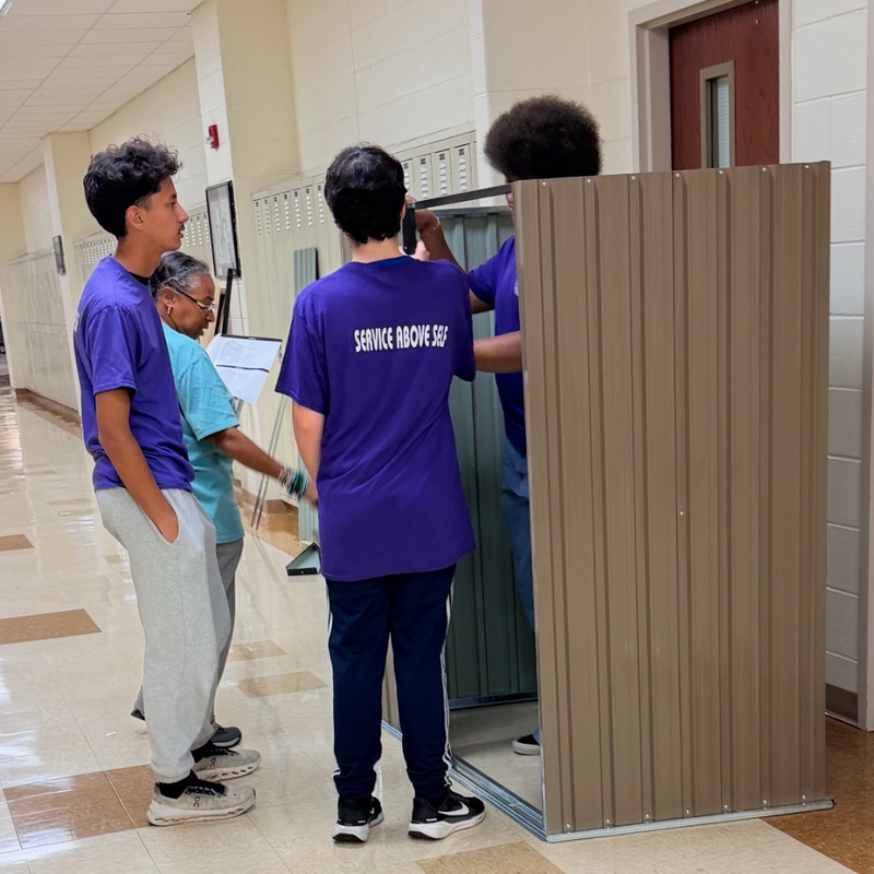 students in purple shirts standing next to a browndoor