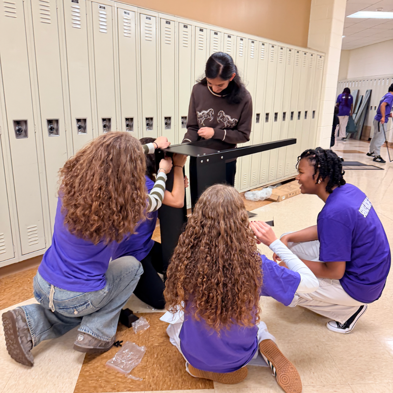 five students sit and stand putting  together a garden box