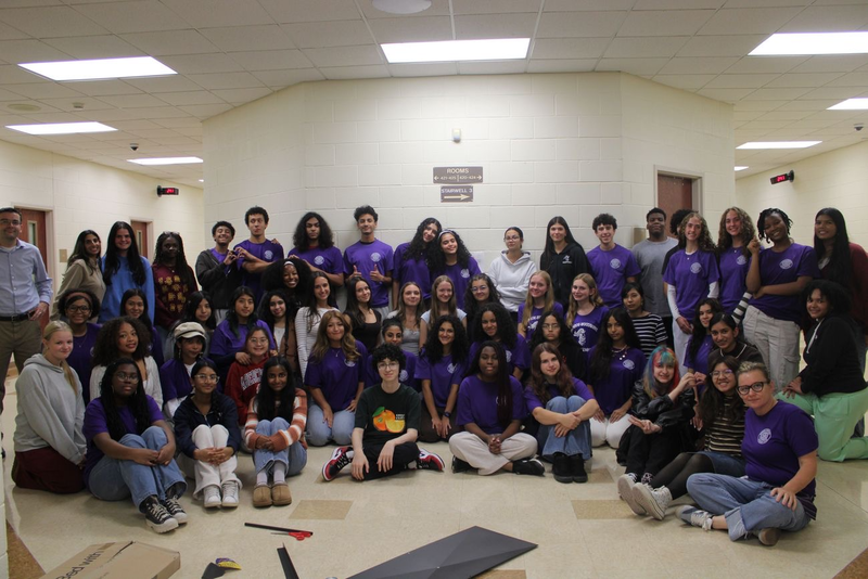 a group of students sitting and standing in a hallway